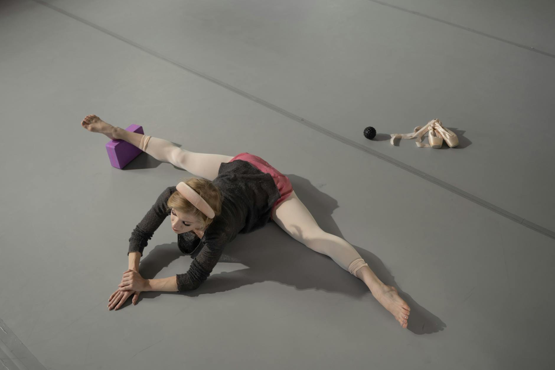 Tancerka baletowa wykonuje głęboki skłon w sali do ćwiczeń