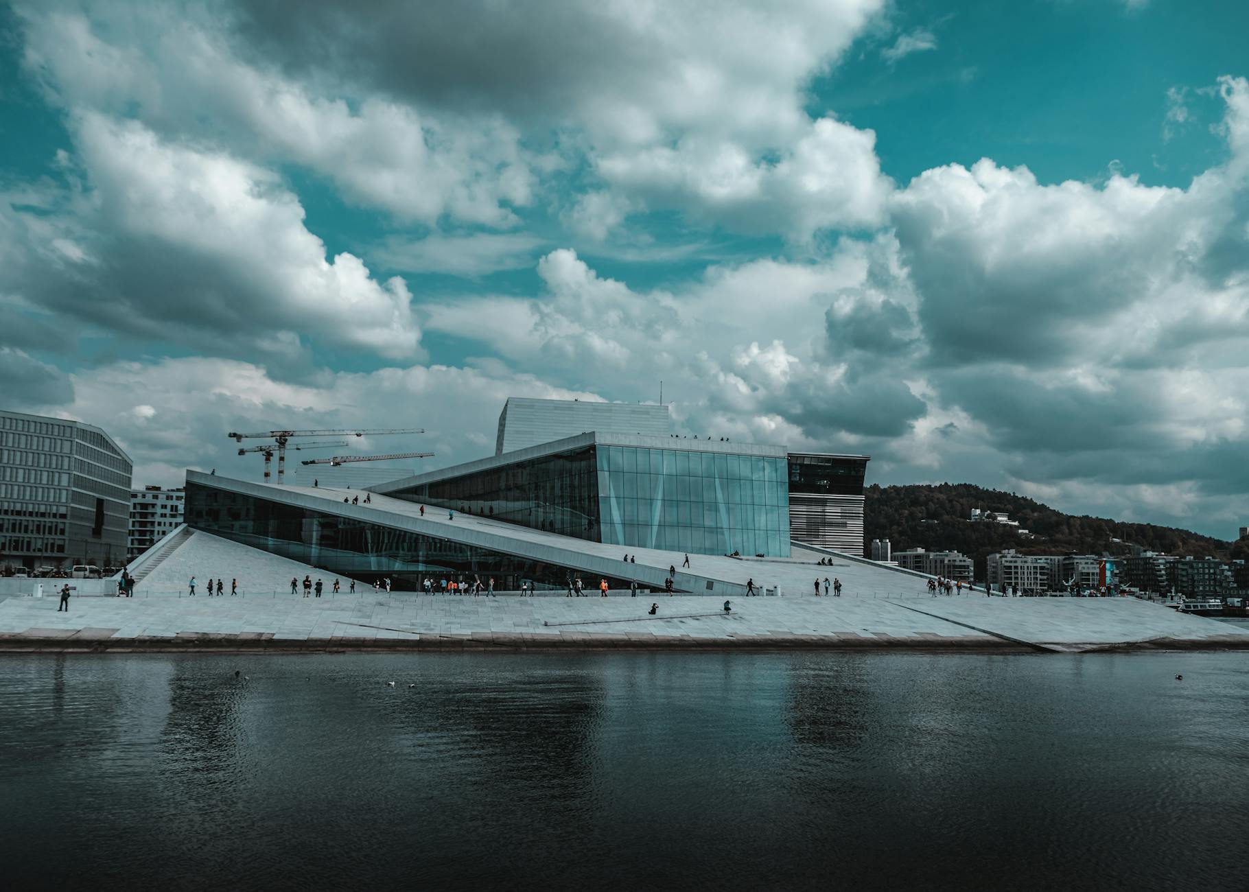 Opera w Oslo nad wodą, nowoczesny budynek w chmurach odbity w tafli fiordu