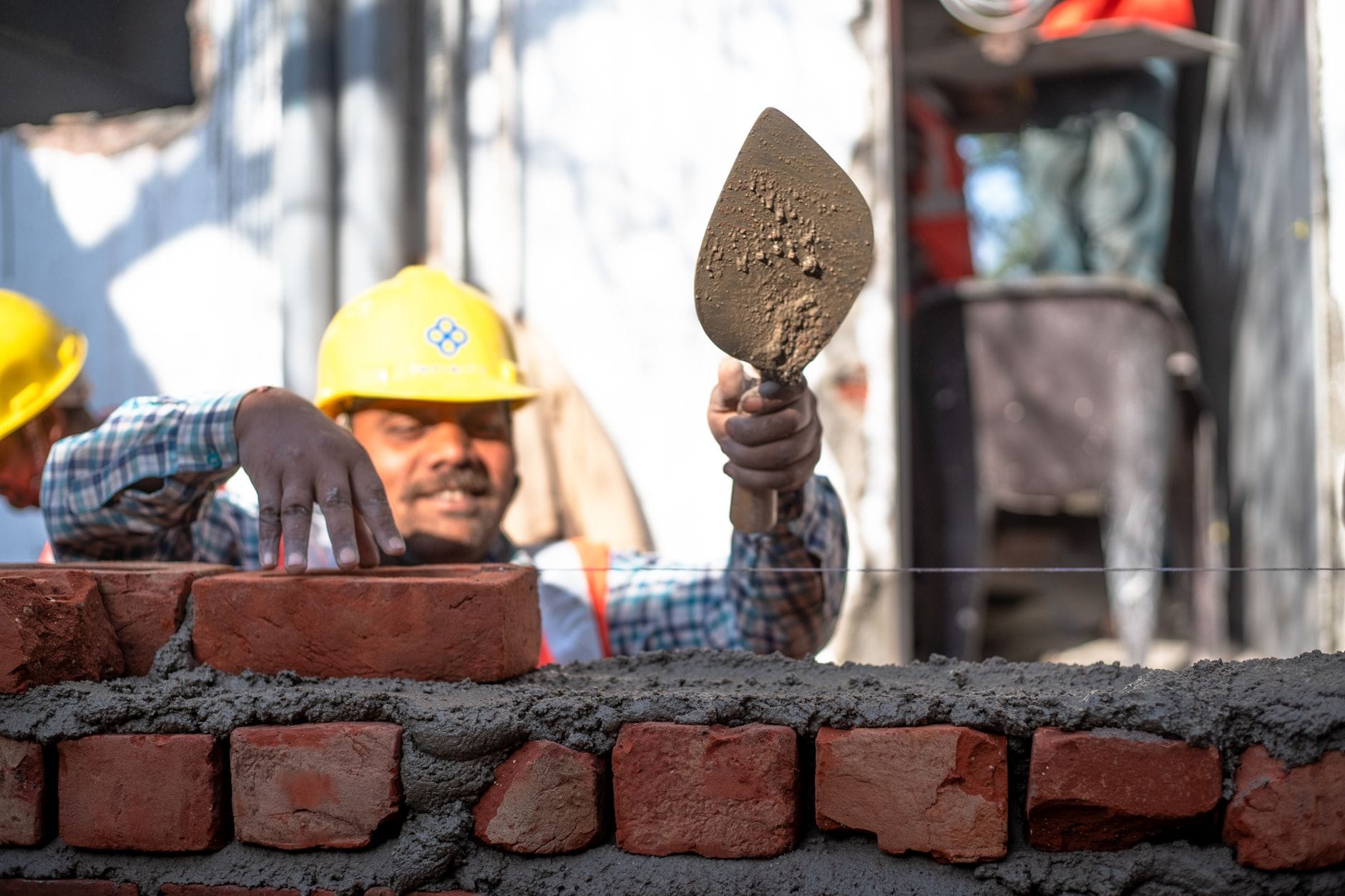 Dwóch budowlańców muruje ścianę z cegieł na budowie w Delhi